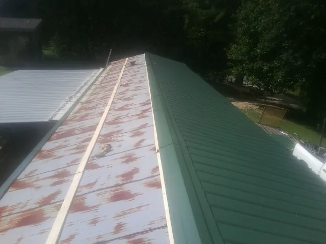 Old rusted panels beside newly installed green metal roofing — Wind Damage Roof Repair by Roofing Brothers in Flemingsburg