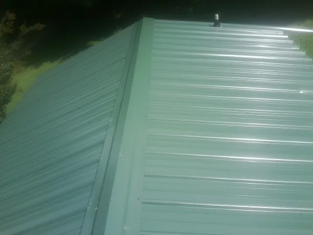 New green metal panels meeting at the ridge of a roof — Flat Roof Repair work by our crew in Flemingsburg