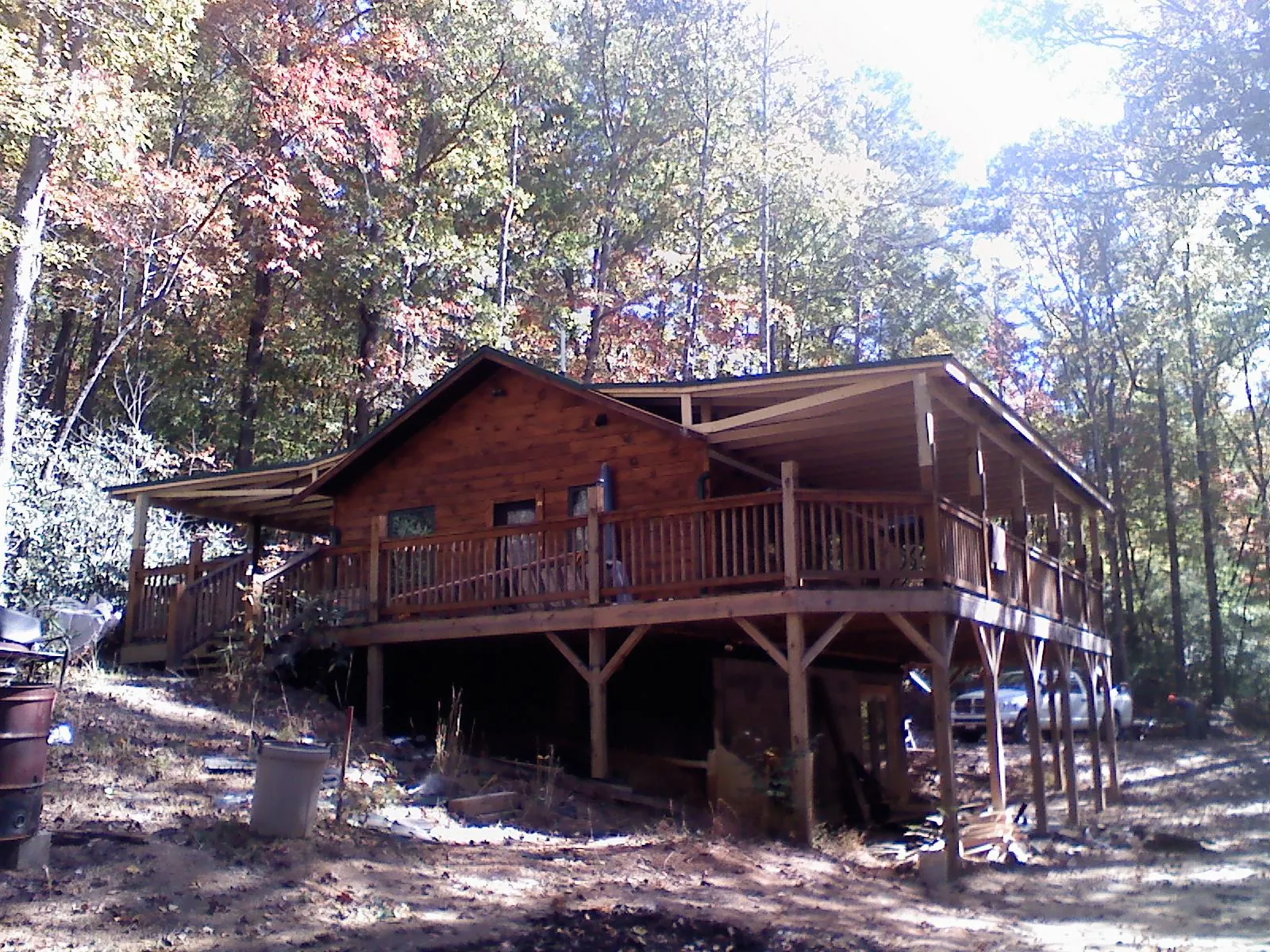 Log cabin with a wraparound porch and metal roof in the fall in Flemingsburg