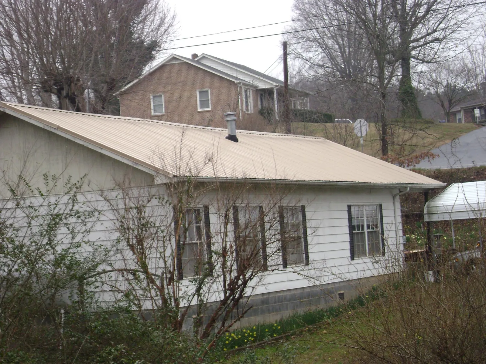 Tan metal roof on a white sided house set into a hillside — Commercial Roofing by Roofing Brothers in Flemingsburg