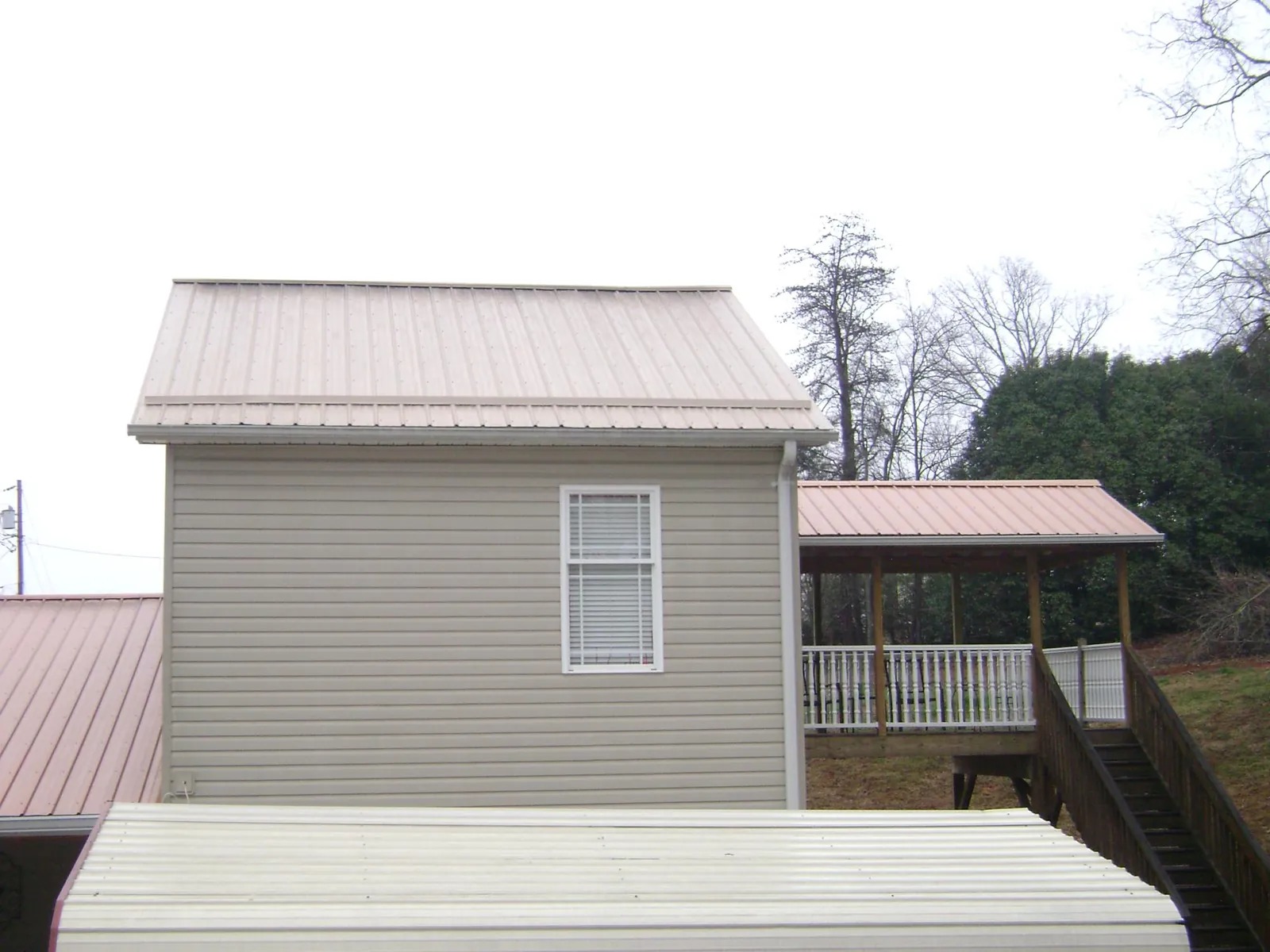 Tan metal roofs on a two story addition and attached porch, from a Roof Replacement job in Flemingsburg