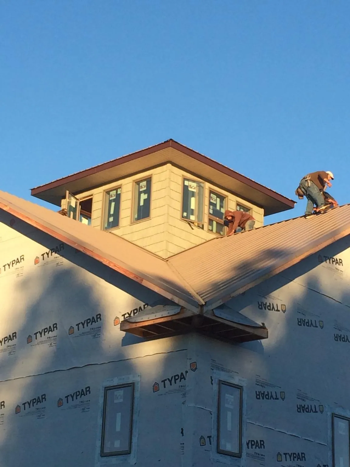 Roofers working around a rooftop cupola on a new metal roof at sunset — Roof Waterproofing in Flemingsburg by Roofing Brothers